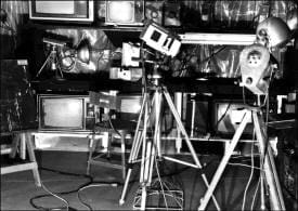 A black and white photo of a camera on a tripod.