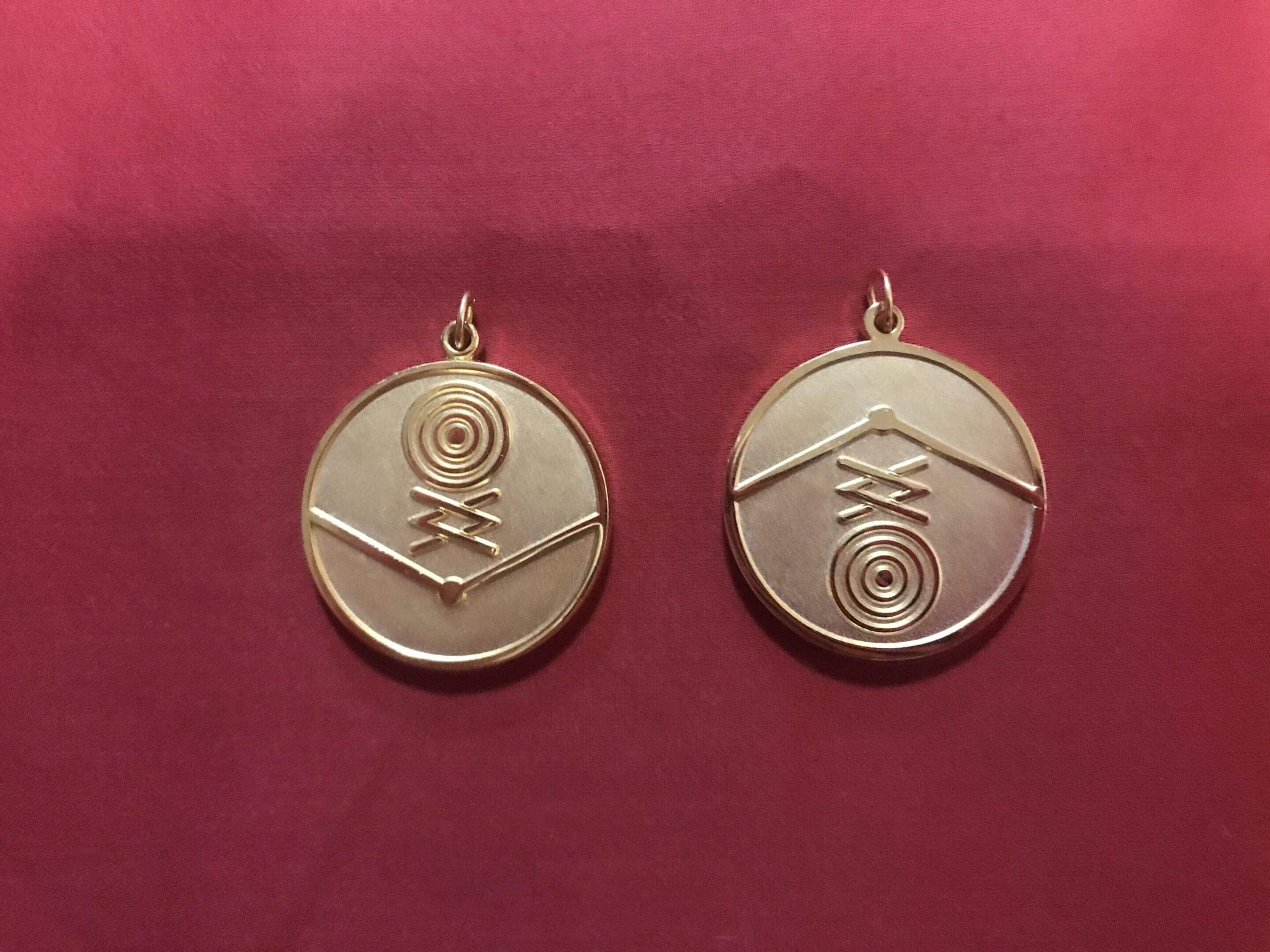 Pair of gold pendants with symbols.
